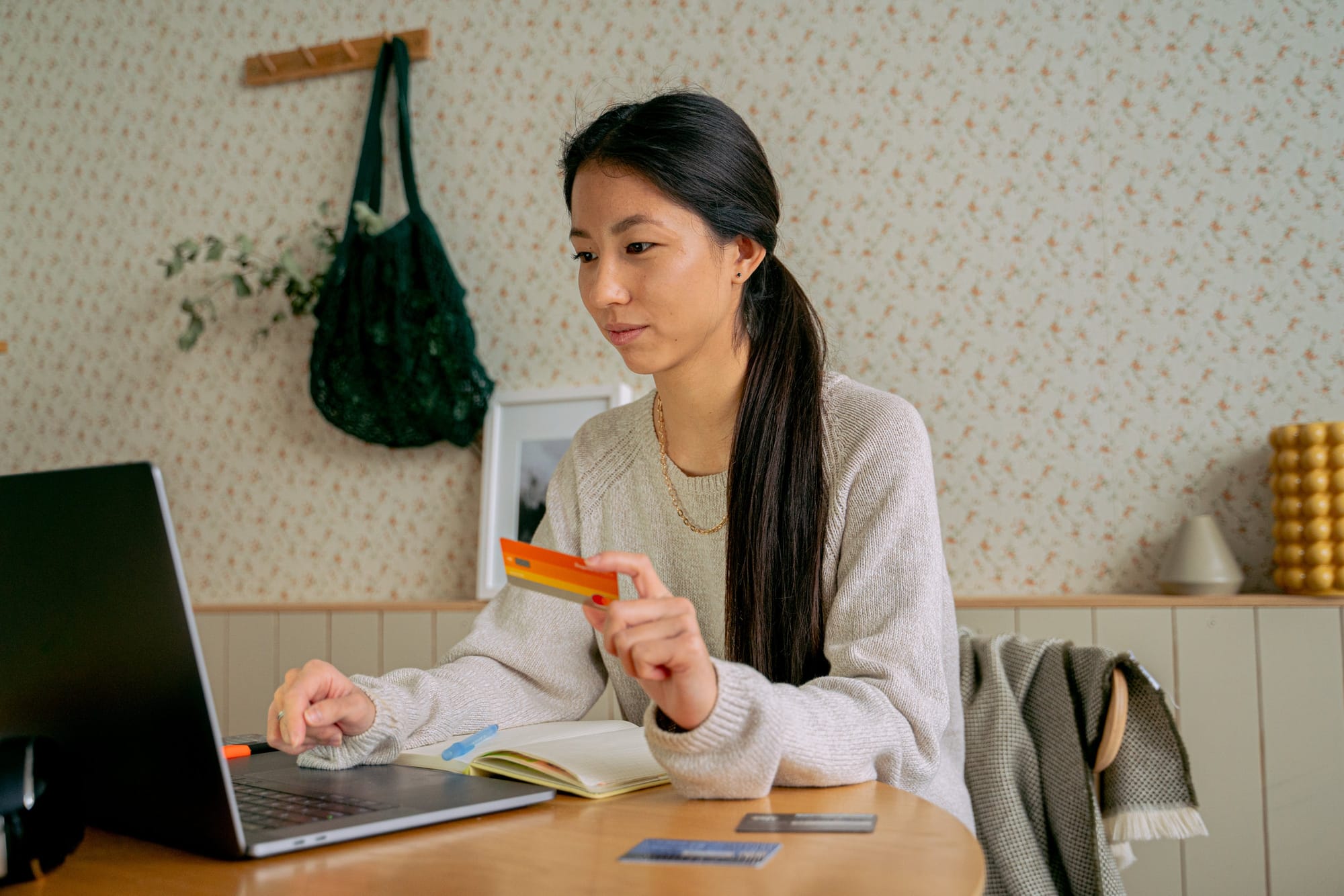 Woman Holding a Card While Using a Laptop