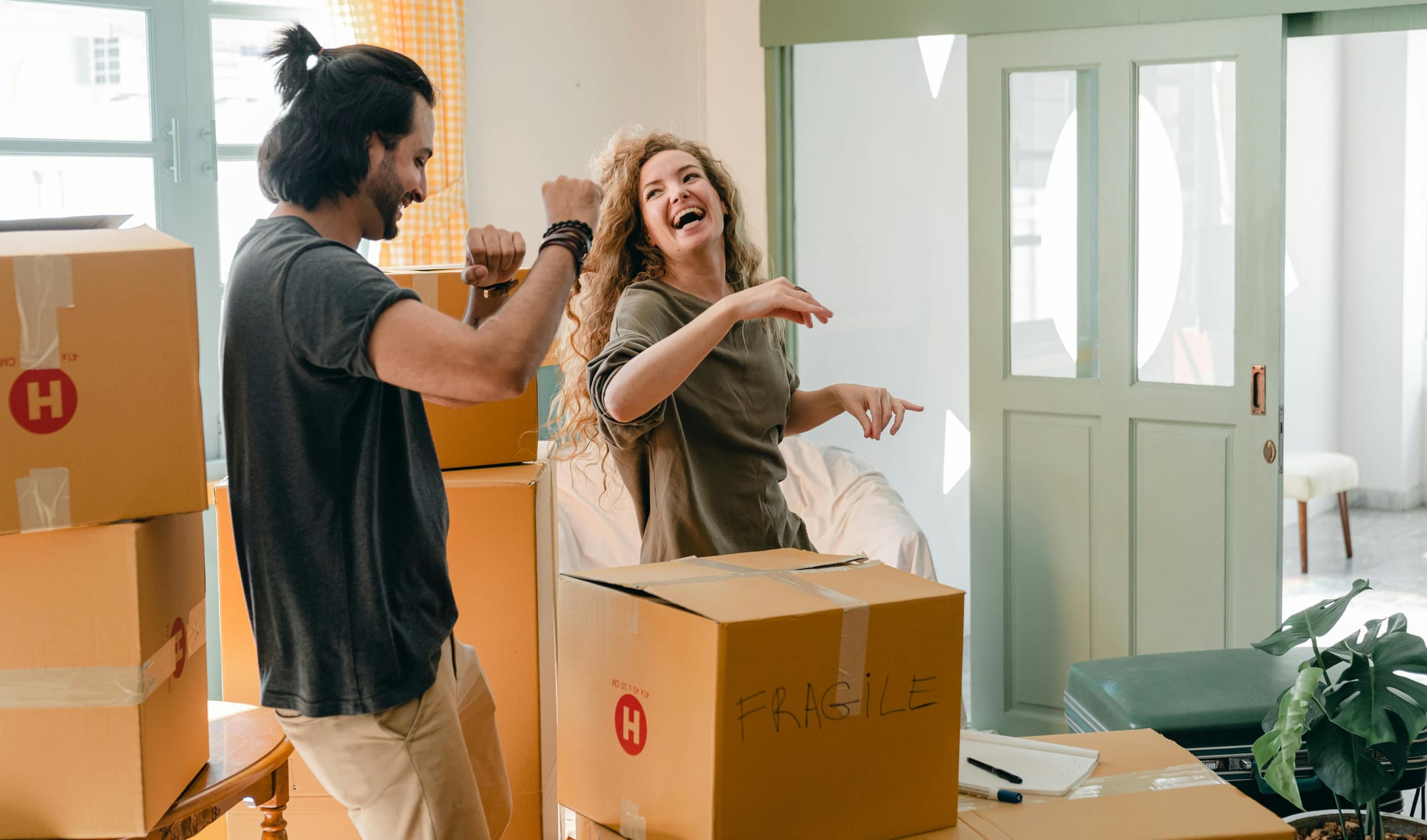 Happy couple unpacking boxes and dancing