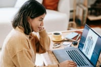 Smiling ethnic remote worker using laptop with photo on screen